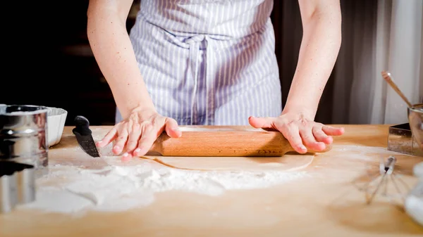 Mãos femininas rolando massa na mesa da cozinha, close-up — Fotografia de Stock