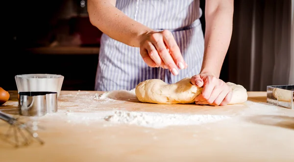 Mani femminili che fanno la pasta sul tavolo di legno — Foto Stock