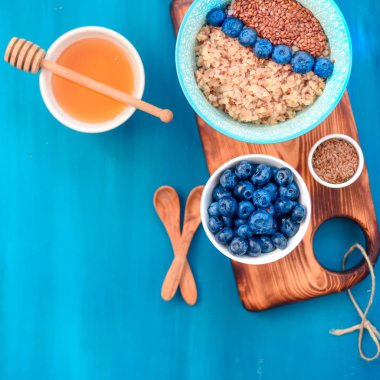 Sağlıklı kahvaltı malzemeleri. Beyaz ahşap arka plan üzerine karabuğday yaban mersini nane bal, üst görünüm, kopya alanı