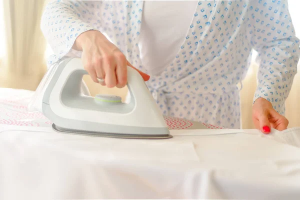 Крупним планом жінка прасує одяг на прасувальній дошці — стокове фото