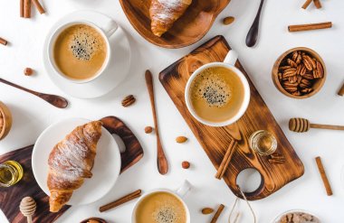 Kontinental kahvaltı yukarıdan yakalanan üst görünümü, düz yatıyordu . offee ve kruvasan, fındık, tarçın, pekan, fındık, bal, badem, kesme tahtası, tahta, kaşık, yumru şeker.