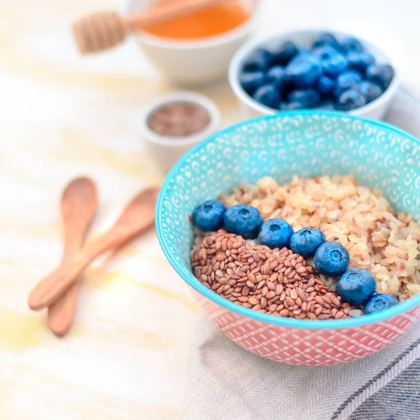 High protein healthy breakfast, buckwheat porridge with blueberries, flax seeds and honey