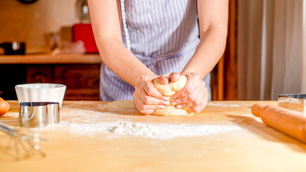 женские руки месить тесто на столе, кухонные принадлежности
