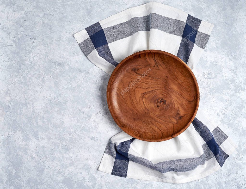 The brown wooden plate on a towel, on blue table, top view