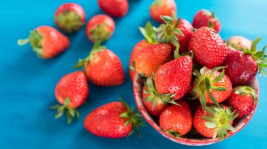 mavi ahşap arka plan üzerinde taze çilek parlak baskılı kase