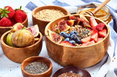 Sağlıklı kahvaltı ve kahvaltı malzemeleri, meyve ve çilek, incir, yaban mersini, çilek, keten ve chia tohumu, bal ile yulaf ezmesi.