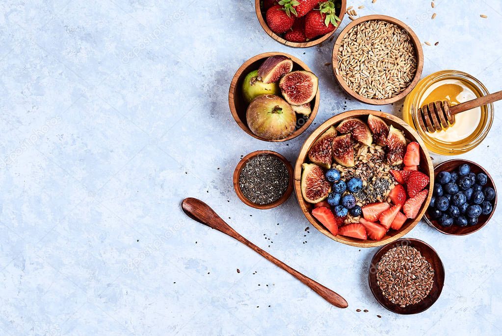 Healthy breakfast and breakfast ingredients, oatmeal with fruits and berries, figs, blueberries, strawberries, flax and chia seeds, honey. Top view, flat lay