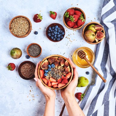 Üst görünüm bal ile lapa yiyen eller gösteren, yaban mersini, mavi ahşap masa arka plan çilek Günaydın, sağlıklı kahvaltı arka plan