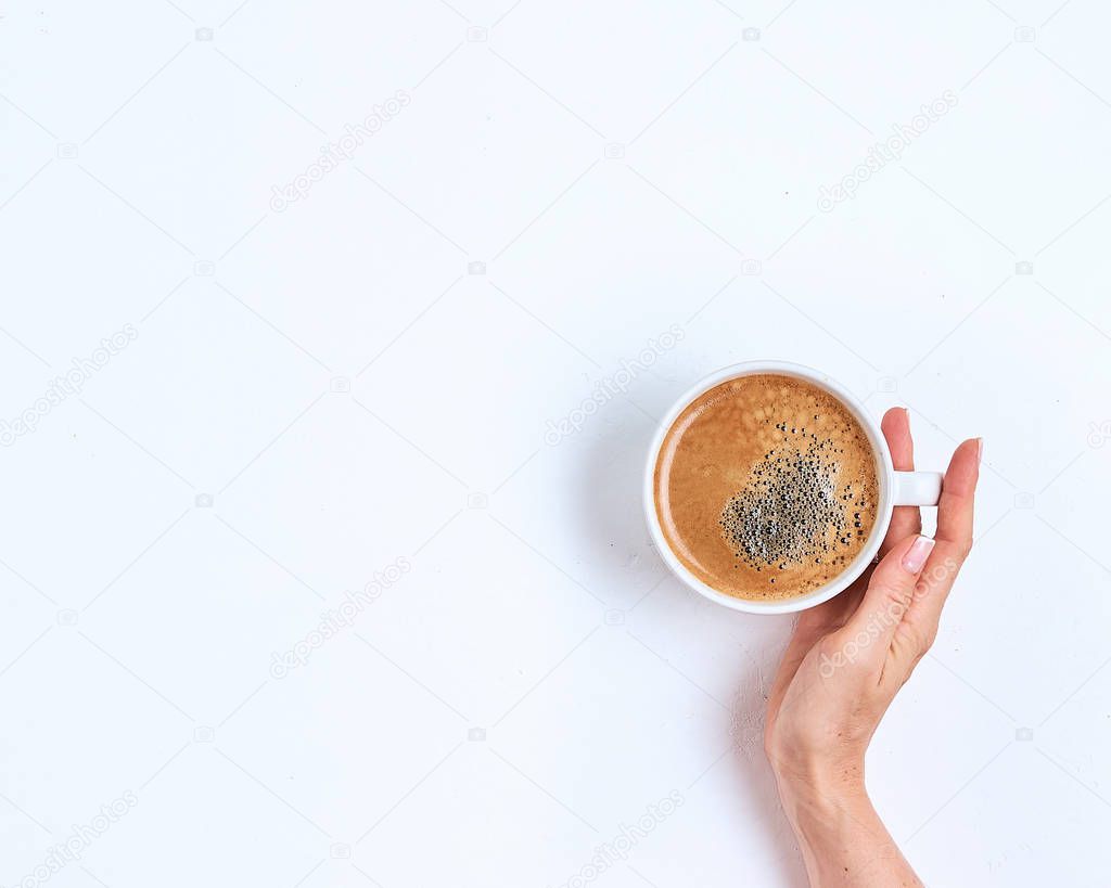 White coffee cup in female hands on a white background. Top view
