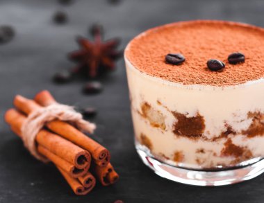 kakao serpilir ve koyu bir arka plan, lüks tatlı üzerinde kahve çekirdekleri ile dekore edilmiş bir bardak gurme tiramisu tatlı