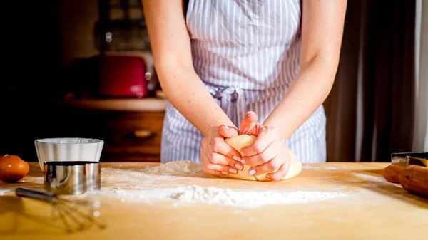 Le mani delle donne impastare l'impasto sul tavolo, accessori cucina — Foto Stock