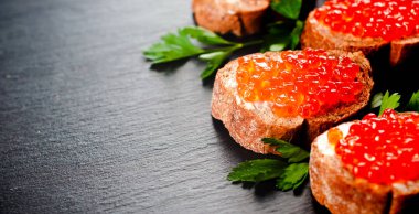 Ekmek arası arduvaz arka plan üzerinde kırmızı havyar.