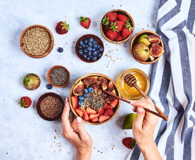Üst görünüm bal ile lapa yiyen eller gösteren, yaban mersini, mavi ahşap masa arka plan çilek Günaydın, sağlıklı kahvaltı arka plan