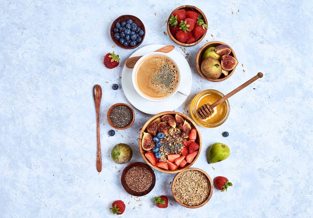 Healthy breakfast and breakfast ingredients, oatmeal with fruits and berries, figs, blueberries, strawberries, flax and chia seeds, honey. Top view, flat lay