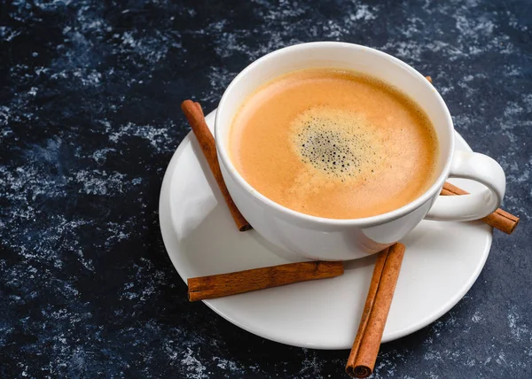 Taza de café con espuma con canela sobre fondo negro — Foto de Stock