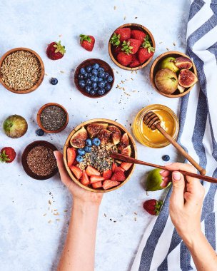 Üst görünüm bal ile lapa yiyen eller gösteren, yaban mersini, mavi ahşap masa arka plan çilek Günaydın, sağlıklı kahvaltı arka plan