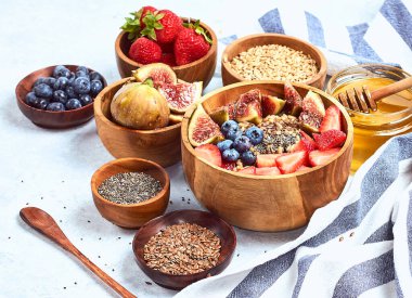 Sağlıklı kahvaltı ve kahvaltı malzemeleri, meyve ve çilek, incir, yaban mersini, çilek, keten ve chia tohumu, bal ile yulaf ezmesi.