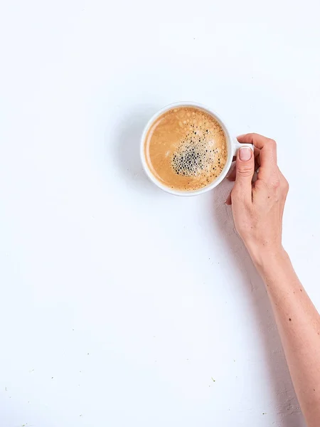 Xícara de café branco em mãos femininas em um fundo branco. Vista superior — Fotografia de Stock