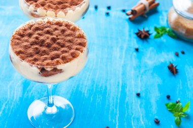 Ahşap arka planda kakaolu kokteyl bardağında lüks bir tiramisu tatlısı.