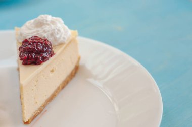 Kremalı beyaz tabakta reçelli cheesecake.