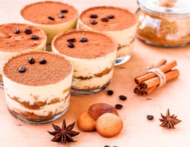 Kakaolu bardakta gurme tiramisu tatlısı ve koyu arkaplanda kahve çekirdekleri.