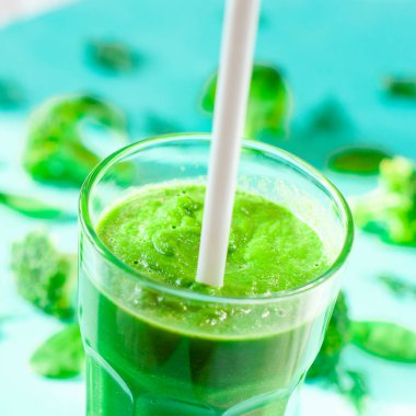 Bir bardak brokoli suyu, bambu hasırında, yeşil arka planda.