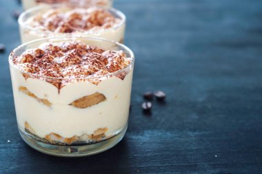 Koyu arkaplanda kakao tozuyla süslenmiş gözlüklerle nefis tiramisu.