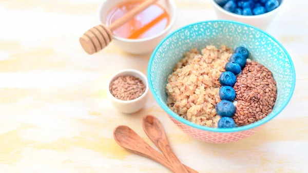 High protein healthy breakfast, buckwheat porridge with blueberries, flax seeds and honey