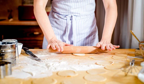 Kvinnliga händer rullar ut deg på köksbordet, närbild — Stockfoto