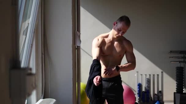 Молодой мужчина снимает рубашку на обнаженном мышечном туловище — стоковое видео