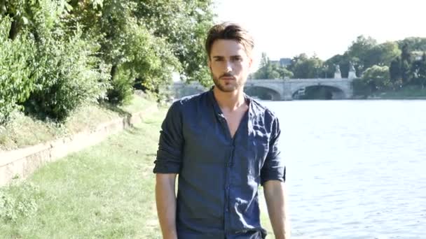 Un joven guapo junto al río en la ciudad — Vídeos de Stock