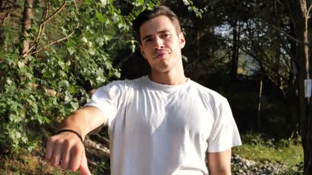 Молодой человек в природе делает знак "опусти палец" — стоковое видео