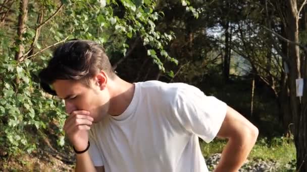 Молодий чоловік кашляє в природі — стокове відео