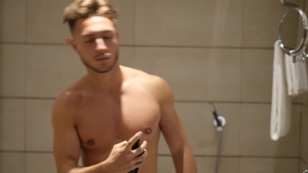 Молодой человек в ванной комнате, распыляя одеколон или духи — стоковое видео