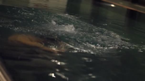 Junger Mann entspannt sich nachts im Schwimmbad — Stockvideo