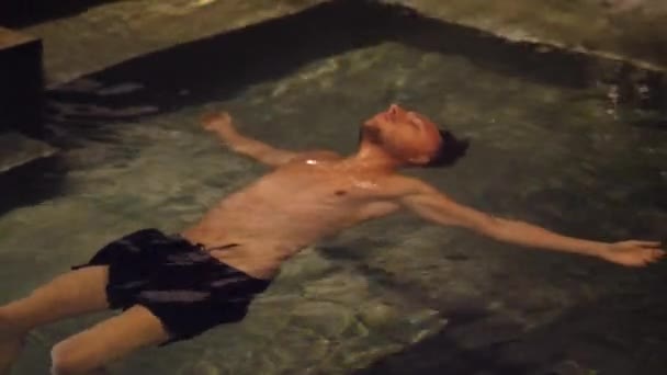 Genç adam gece yüzme havuzunda rahatlatıcı — Stok video