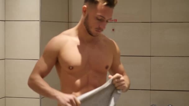 Молодой спортсмен надевает свитер в ванной комнате — стоковое видео