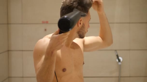 Jovem sem camisa secando o cabelo com secador de cabelo — Vídeo de Stock