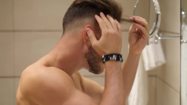 Shirtless musclé beau jeune homme fixant les cheveux — Video