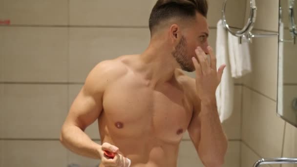 Hombre joven guapo aplicando crema hidratante — Vídeo de stock