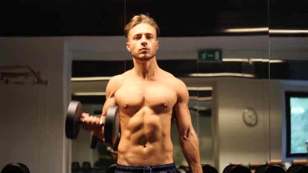 Knappe jongeman die biceps traint in de sportschool — Stockvideo