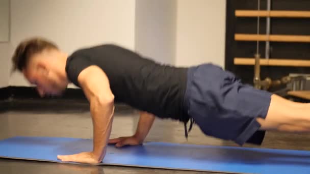 Knappe jongeman doen push-ups oefening op mat — Stockvideo