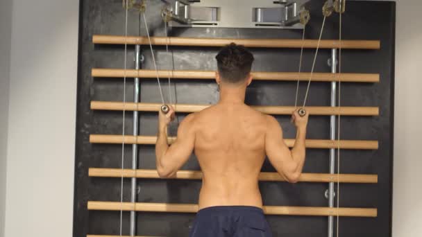 Muskulöser junger Mann, der wieder an der Sprossenwand trainiert — Stockvideo