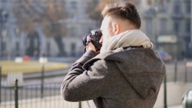 Yakışıklı genç fotoğrafçı dışarıda fotoğraf çekiyor.