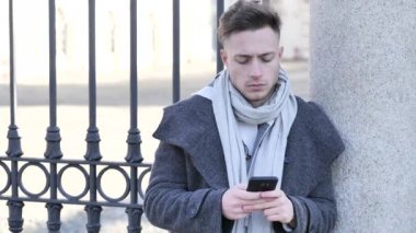 Metin yazmak için cep telefonu kullanan yakışıklı modacı.