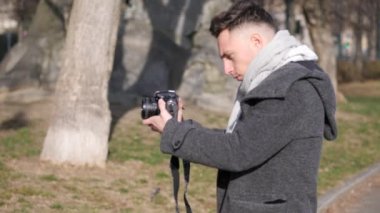 Yakışıklı genç fotoğrafçı dışarıda video çekiyor.