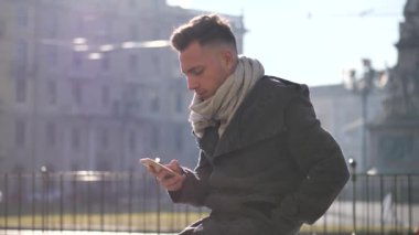 Metin yazmak için cep telefonu kullanan yakışıklı modacı.