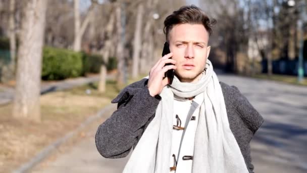 Joven en la ciudad, caminando y hablando con alguien en el teléfono inteligente — Vídeo de stock