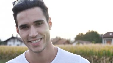 Kameraya bakarak doğa ortamında, gülümseyen çekici genç adamın headshot