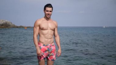 Yakışıklı genç uygun adam, el ile ok işareti yapıyor, arkasında deniz ile, büyük boşaltmak